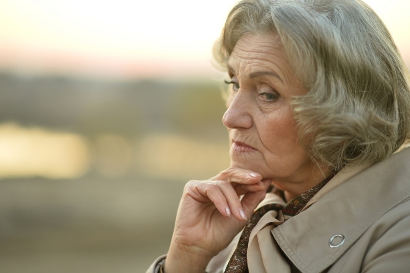 Older woman pondering her thoughts outside