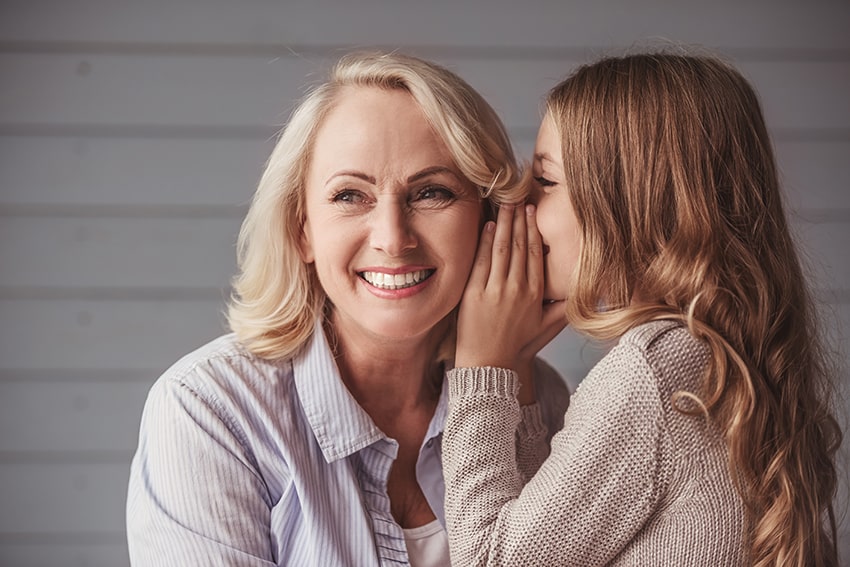Little girl whispering to her Grandmother. Is it a secret about tooth decay and oral bacteria?
