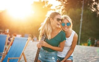 2 young women smiling and laughing on the beach