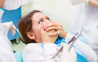 A young woman with dental anxiety rests her hands over her mouth in fear while sitting in a dental chair. When using these categories, however, most of us probably wouldn’t include whether or not we’re afraid of the dentist. But as a new study suggests, certain categories may be directly related to this exact metric.