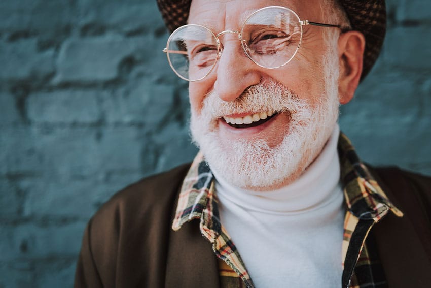 older man with large glasses shows of his big smile