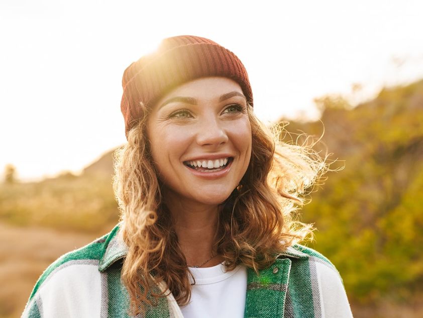Young woman in beanie walking in the sun and smiling